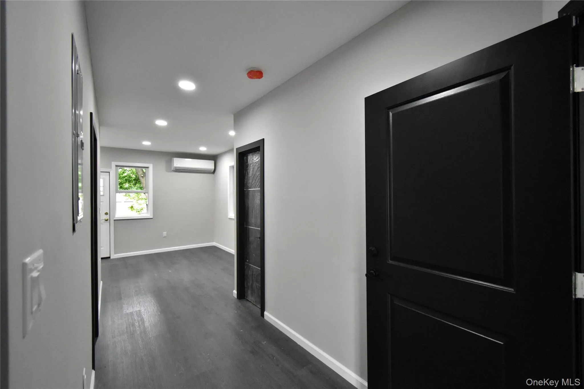 Hallway with recessed lighting, dark wood-type flooring, and a wall mounted air conditioner Hallway with recessed lighting, dark wood-type flooring, and a wall mounted air conditioner
