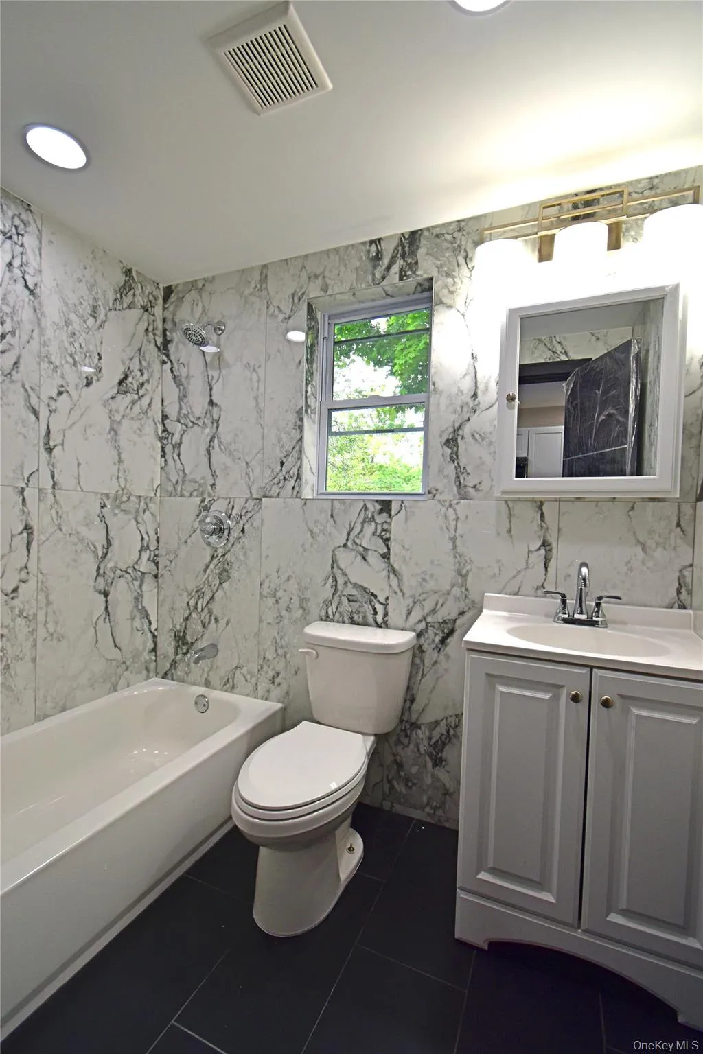 Bathroom with tile walls, vanity, shower / bath combination, tile patterned flooring, and recessed lighting Bathroom with tile walls, vanity, shower / bath combination, tile patterned flooring, and recessed lighting