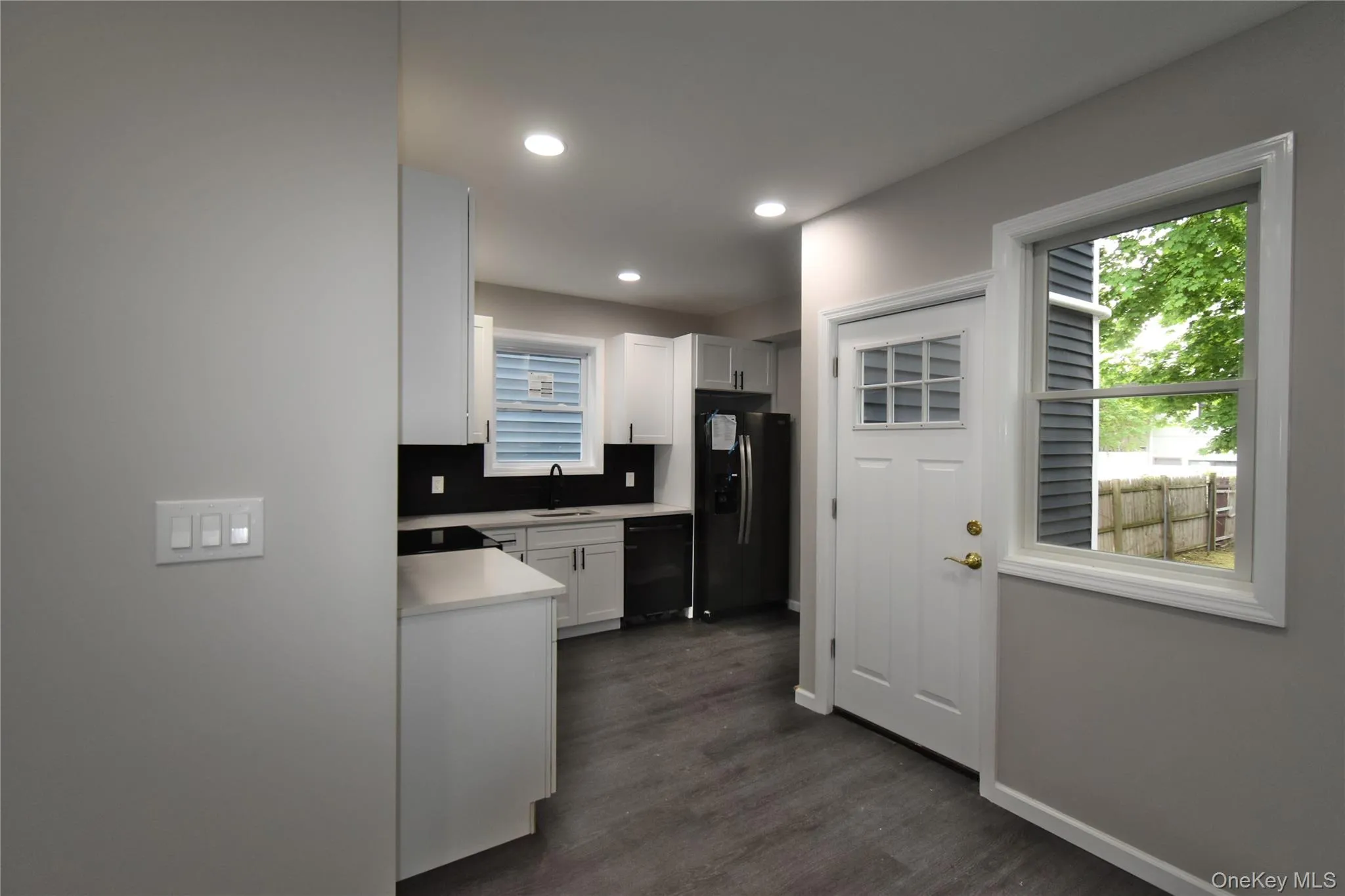 Kitchen with refrigerator with ice dispenser, light countertops, white cabinets, dark wood finished floors, and recessed lighting Kitchen with refrigerator with ice dispenser, light countertops, white cabinets, dark wood finished floors, and recessed lighting