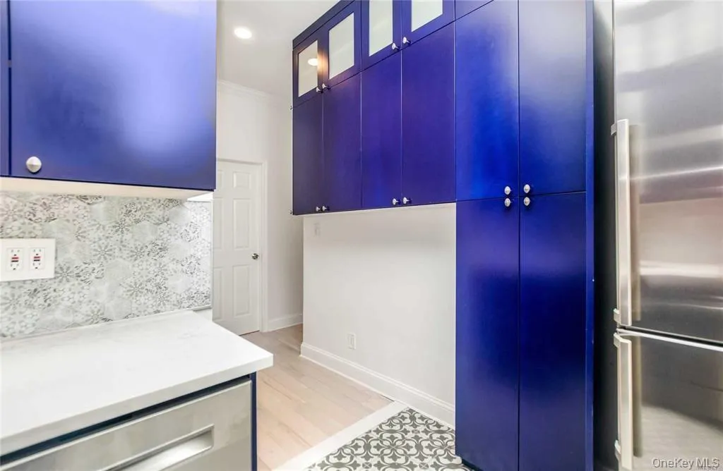 Kitchen featuring appliances with stainless steel finishes, crown molding, light countertops, glass insert cabinets, and backsplash Kitchen featuring appliances with stainless steel finishes, crown molding, light countertops, glass insert cabinets, and backsplash