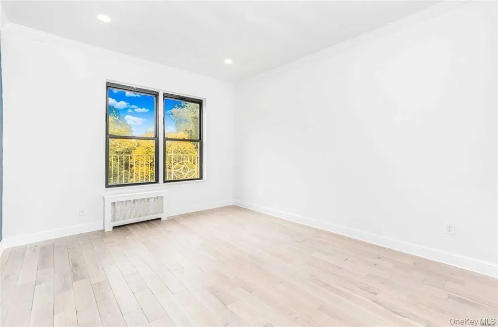 Spare room with radiator heating unit, light wood-style floors, ornamental molding, and recessed lighting Spare room with radiator heating unit, light wood-style floors, ornamental molding, and recessed lighting