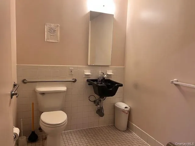 Half bathroom featuring tile patterned flooring and tile walls Half bathroom featuring tile patterned flooring and tile walls