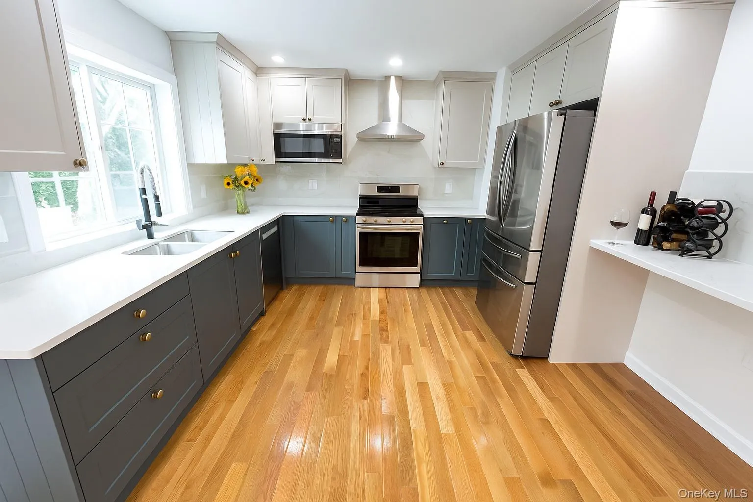 Kitchen featuring appliances with stainless steel finishes, light wood finished floors, wall chimney exhaust hood, white cabinets, and recessed lighting Kitchen featuring appliances with stainless steel finishes, light wood finished floors, wall chimney exhaust hood, white cabinets, and recessed lighting