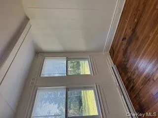 Unfurnished room featuring dark wood-type flooring, a baseboard heating unit, beamed ceiling, and a decorative wall Unfurnished room featuring dark wood-type flooring, a baseboard heating unit, beamed ceiling, and a decorative wall