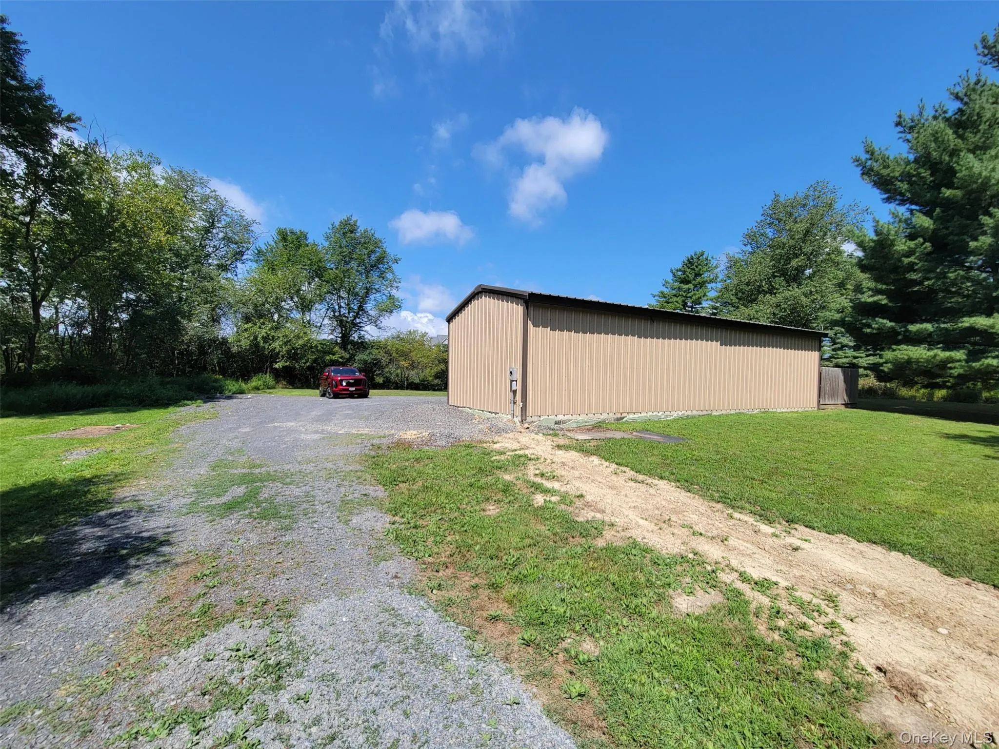 View of side of property with a pole building, gravel driveway, an outbuilding, and a lawn View of side of property with a pole building, gravel driveway, an outbuilding, and a lawn