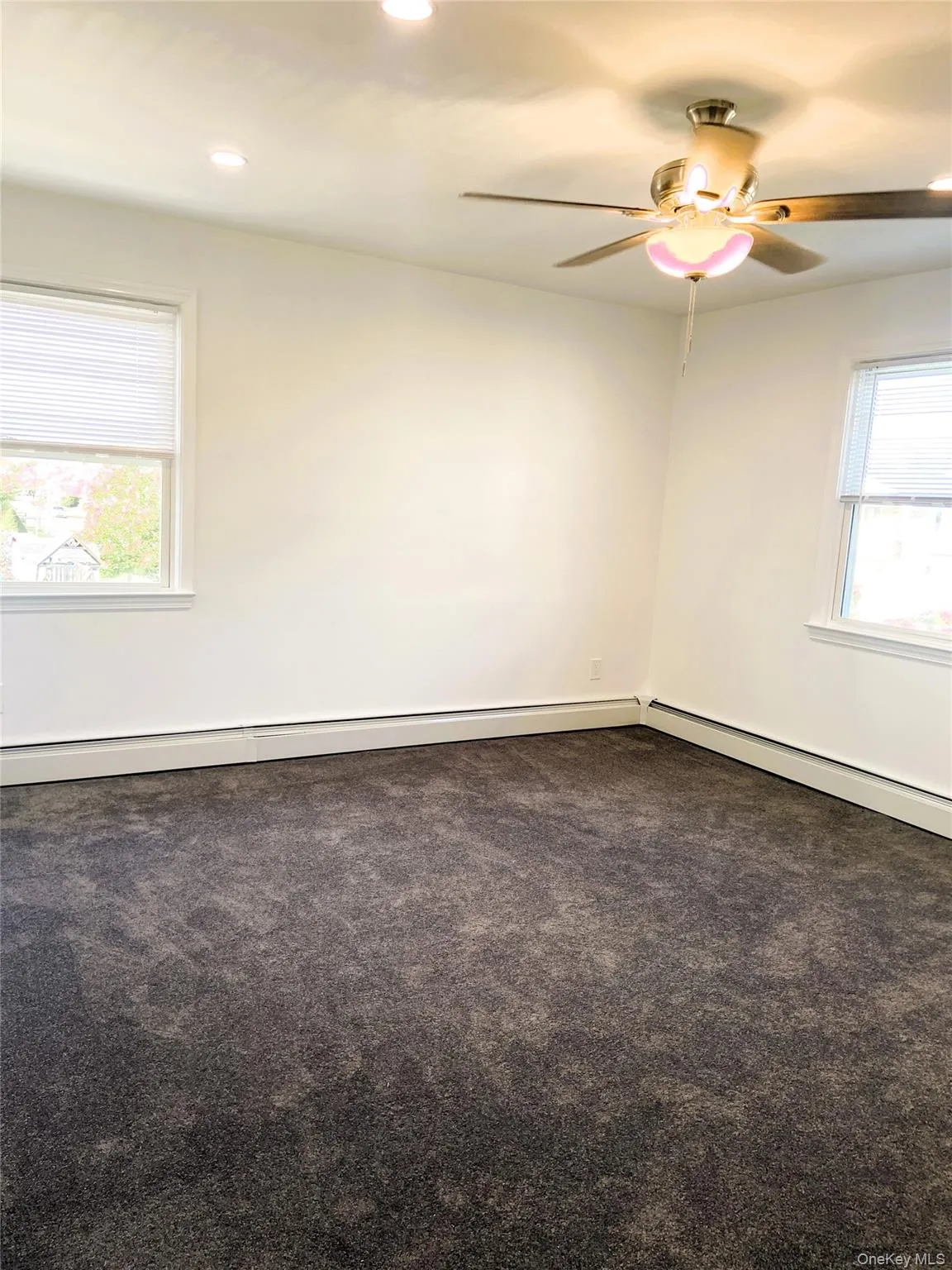 Spare room featuring dark carpet, baseboard heating, recessed lighting, and a ceiling fan Spare room featuring dark carpet, baseboard heating, recessed lighting, and a ceiling fan