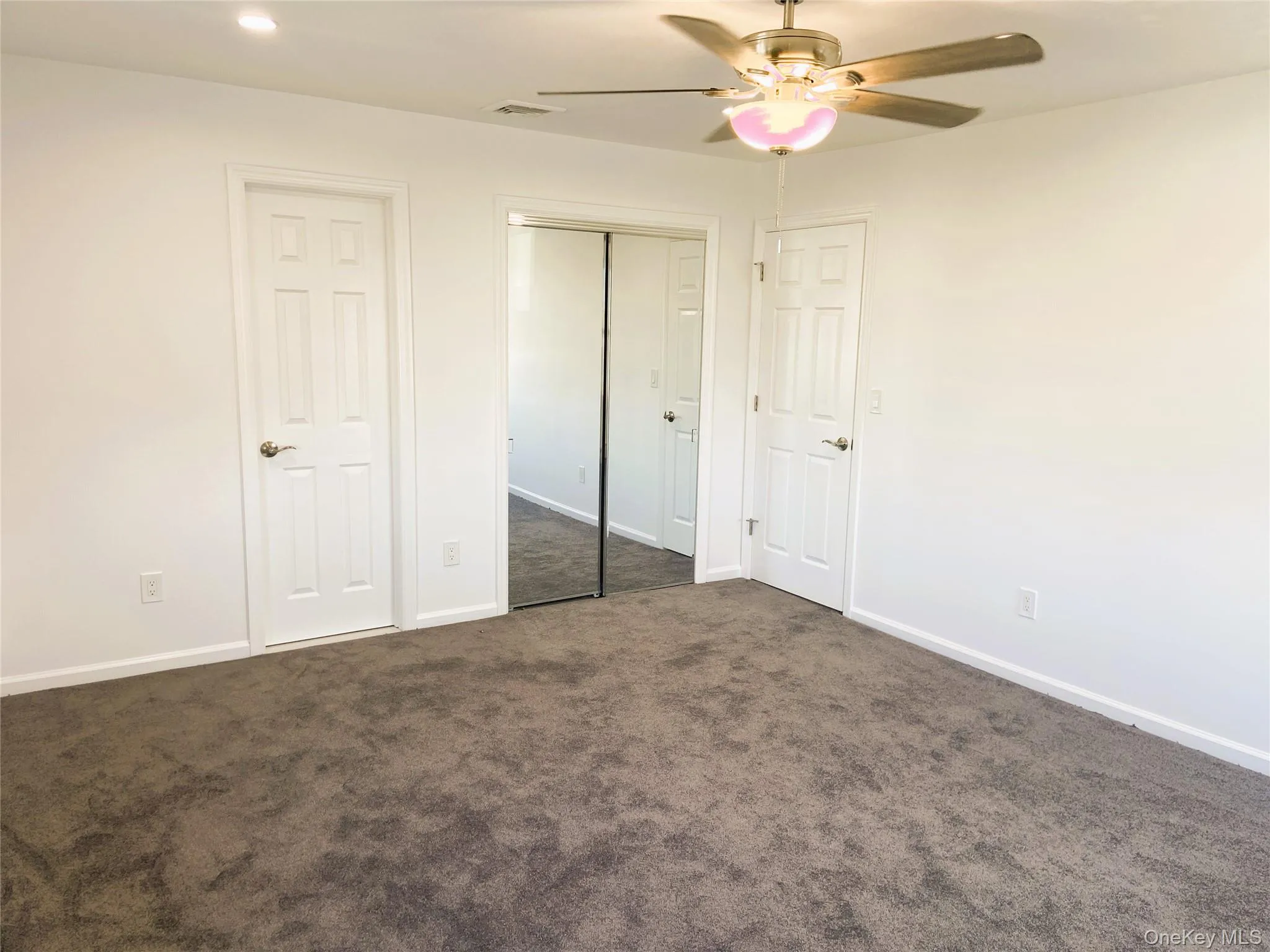Unfurnished bedroom with dark colored carpet and ceiling fan Unfurnished bedroom with dark colored carpet and ceiling fan