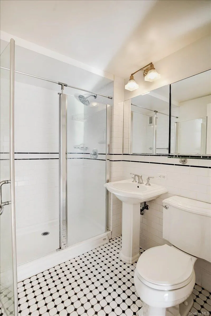 Full bathroom featuring tile walls, a shower stall, and tile patterned floors Full bathroom featuring tile walls, a shower stall, and tile patterned floors