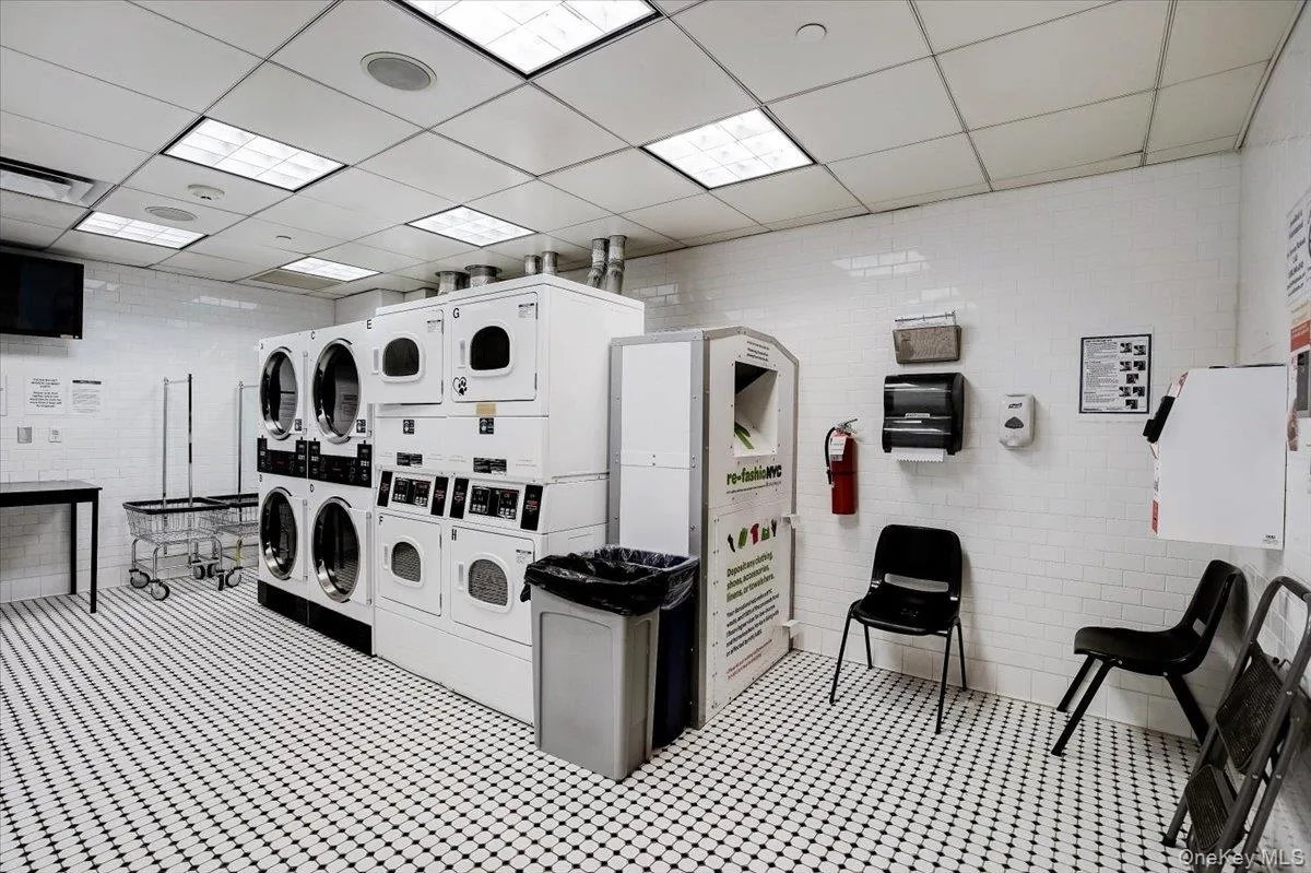 Community laundry room featuring stacked washing machine and dryer, brick wall, light flooring, and separate washer and dryer Community laundry room featuring stacked washing machine and dryer, brick wall, light flooring, and separate washer and dryer