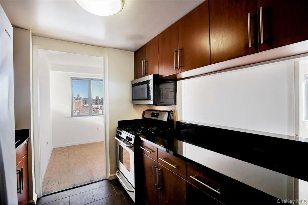 Kitchen featuring stainless steel appliances and dark tile patterned flooring Kitchen featuring stainless steel appliances and dark tile patterned flooring