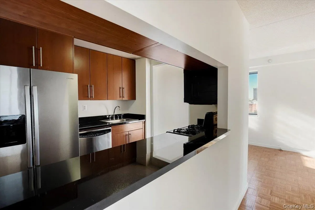Kitchen featuring dark countertops, stainless steel dishwasher, brown cabinets, and stovetop Kitchen featuring dark countertops, stainless steel dishwasher, brown cabinets, and stovetop