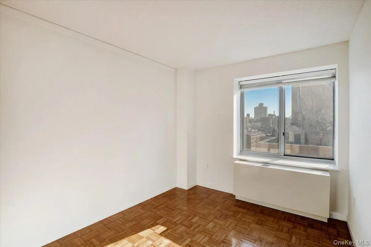Unfurnished room featuring radiator heating unit and a skyline view Unfurnished room featuring radiator heating unit and a skyline view