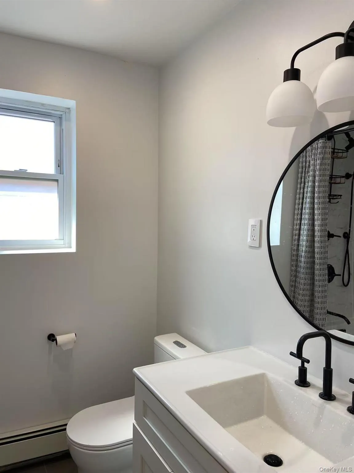 Bathroom with a baseboard radiator, vanity, and a shower with shower curtain Bathroom with a baseboard radiator, vanity, and a shower with shower curtain