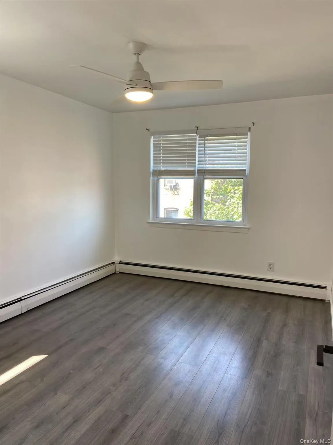 Spare room featuring wood finished floors, a baseboard radiator, and ceiling fan Spare room featuring wood finished floors, a baseboard radiator, and ceiling fan