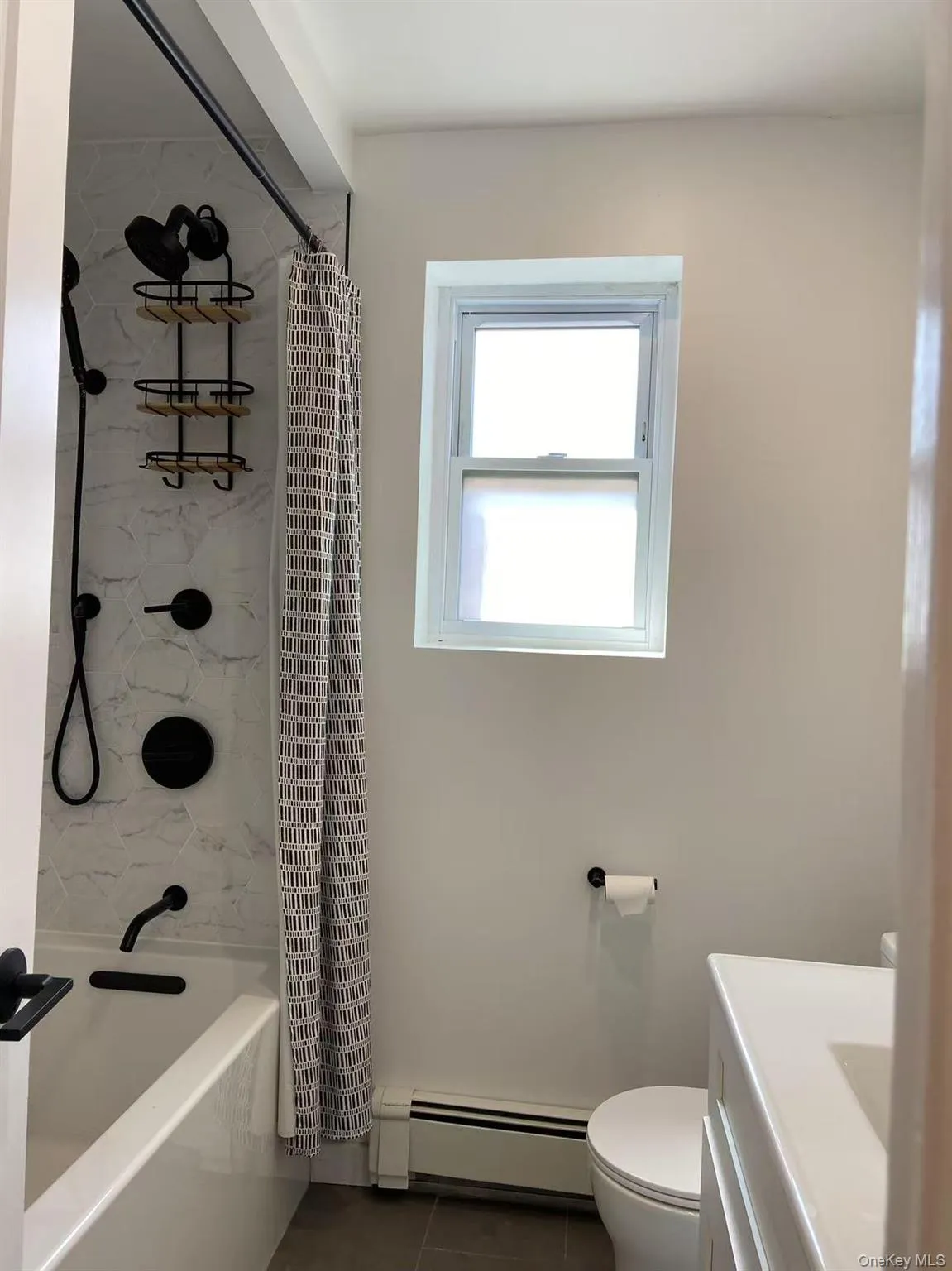 Full bathroom featuring a baseboard radiator, vanity, tile patterned floors, and shower / tub combo Full bathroom featuring a baseboard radiator, vanity, tile patterned floors, and shower / tub combo