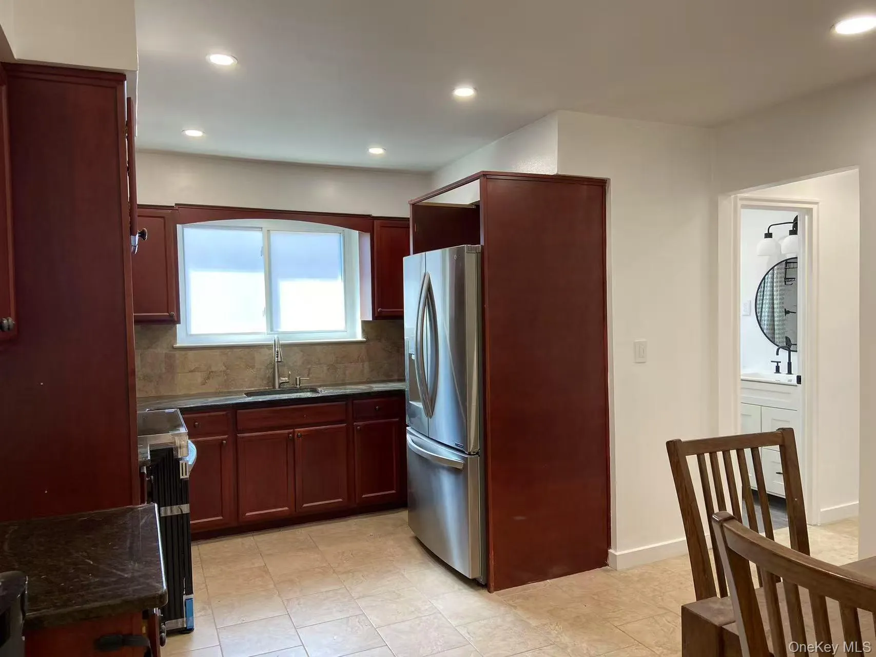 Kitchen with reddish brown cabinets, stainless steel refrigerator with ice dispenser, recessed lighting, decorative backsplash, and range Kitchen with reddish brown cabinets, stainless steel refrigerator with ice dispenser, recessed lighting, decorative backsplash, and range