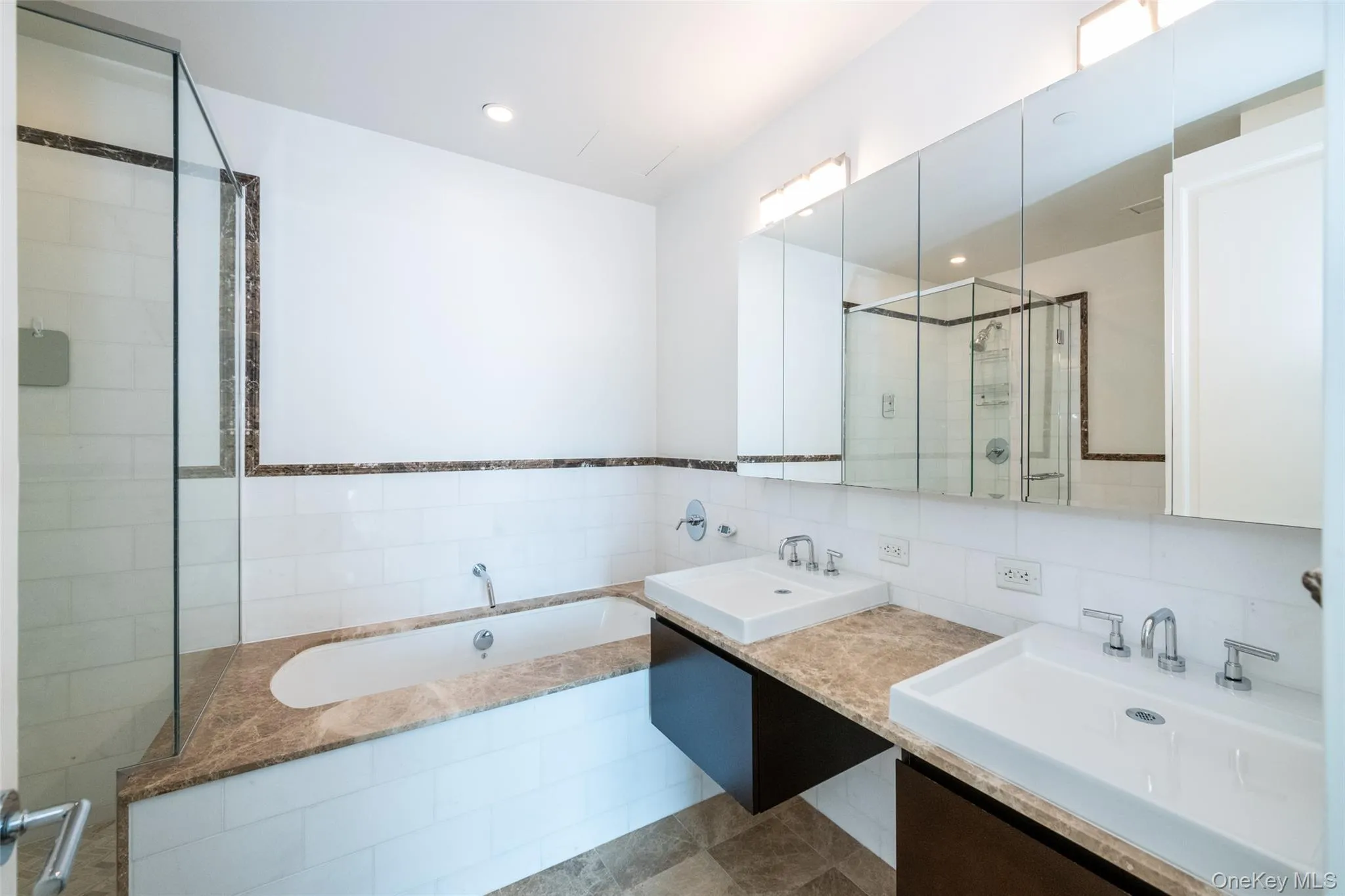 Bathroom featuring double vanity, a garden tub, tile walls, recessed lighting, and a stall shower Bathroom featuring double vanity, a garden tub, tile walls, recessed lighting, and a stall shower
