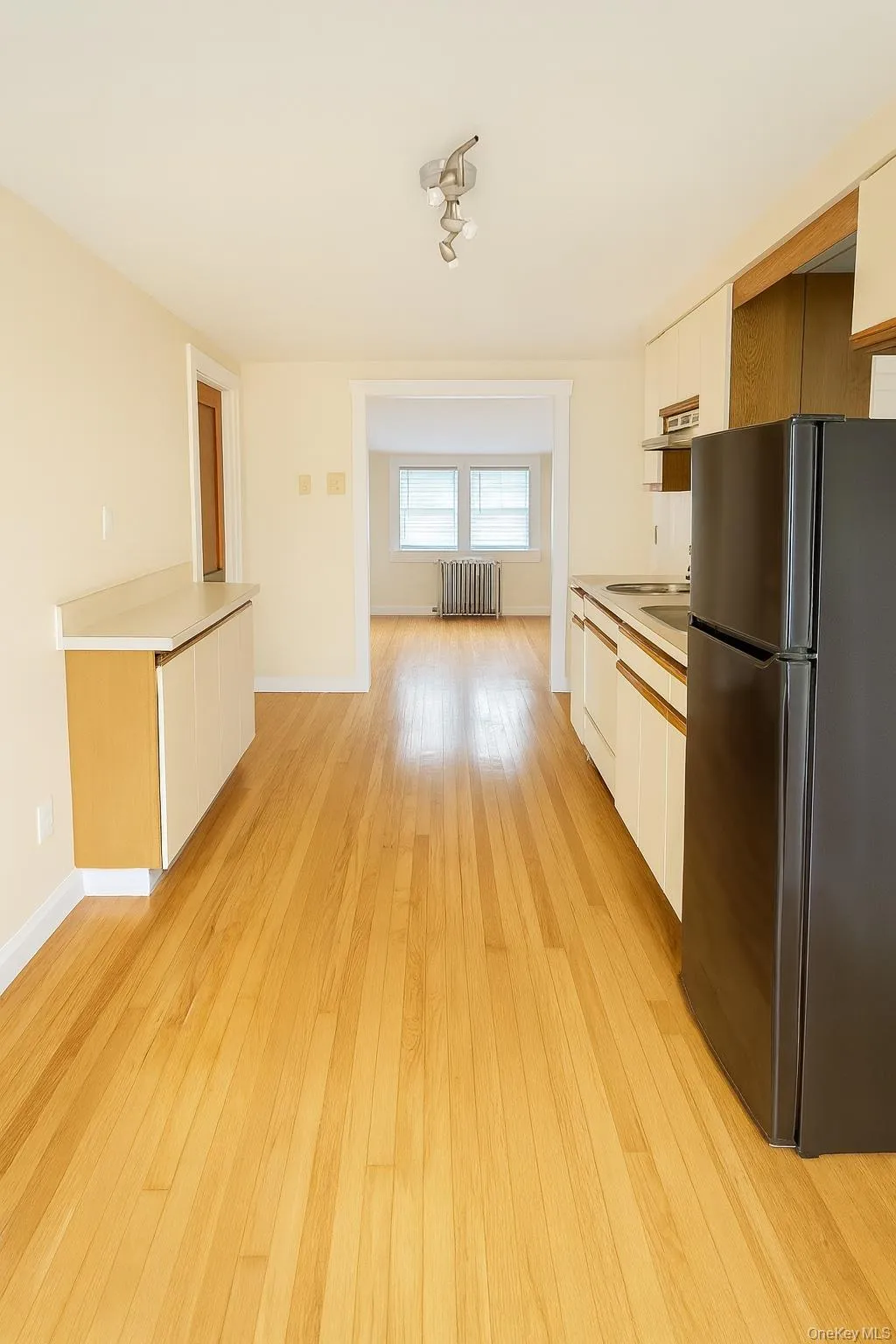 Kitchen with freestanding refrigerator, white cabinets, and light wood-type flooring Kitchen with freestanding refrigerator, white cabinets, and light wood-type flooring