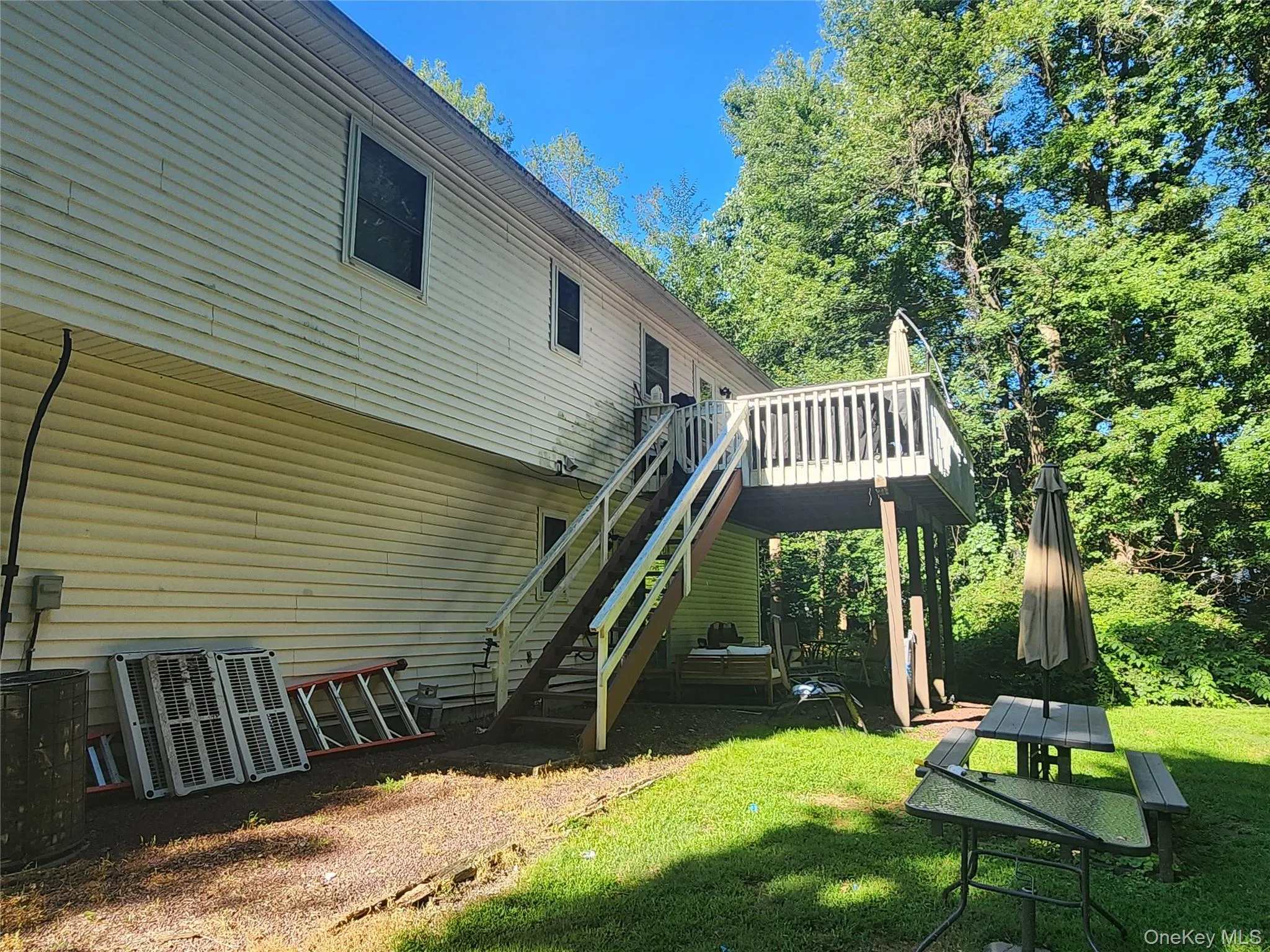 Back of house with stairway, a wooden deck, and a lawn Back of house with stairway, a wooden deck, and a lawn