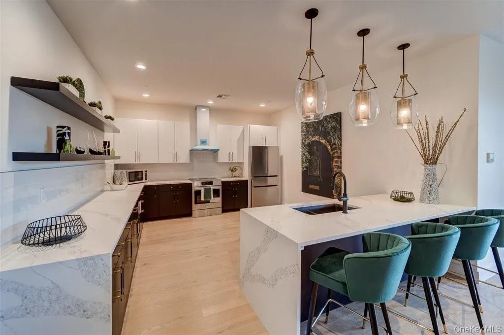 Kitchen featuring open shelves, a peninsula, stainless steel appliances, white cabinetry, and light wood finished floors Kitchen featuring open shelves, a peninsula, stainless steel appliances, white cabinetry, and light wood finished floors
