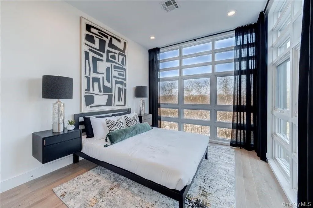 Bedroom featuring expansive windows, light wood-type flooring, and recessed lighting Bedroom featuring expansive windows, light wood-type flooring, and recessed lighting