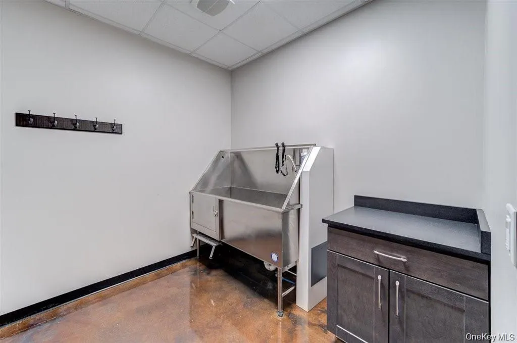 Miscellaneous room with pet washing station, concrete flooring, and a drop ceiling Miscellaneous room with pet washing station, concrete flooring, and a drop ceiling