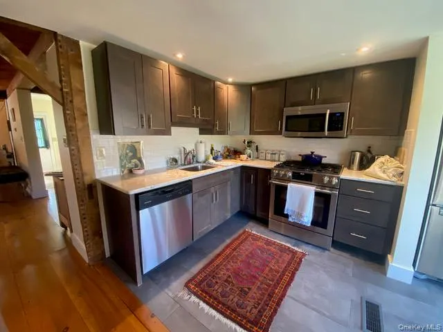 Kitchen featuring appliances with stainless steel finishes, tasteful backsplash, light stone countertops, dark brown cabinets, and recessed lighting Kitchen featuring appliances with stainless steel finishes, tasteful backsplash, light stone countertops, dark brown cabinets, and recessed lighting