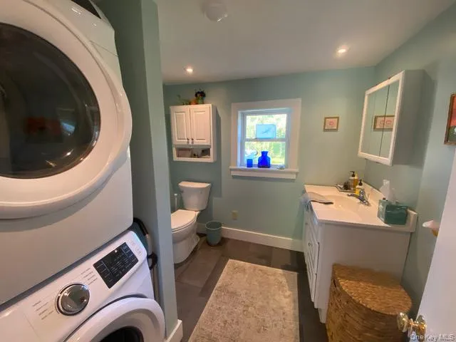 Bathroom featuring vanity, stacked washer / drying machine, recessed lighting, and dark wood-style flooring Bathroom featuring vanity, stacked washer / drying machine, recessed lighting, and dark wood-style flooring