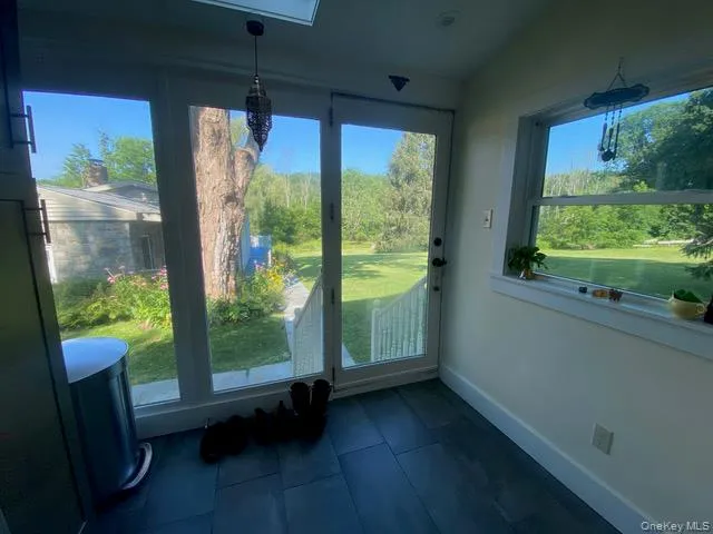 Doorway to outside featuring tile patterned floors and lofted ceiling Doorway to outside featuring tile patterned floors and lofted ceiling