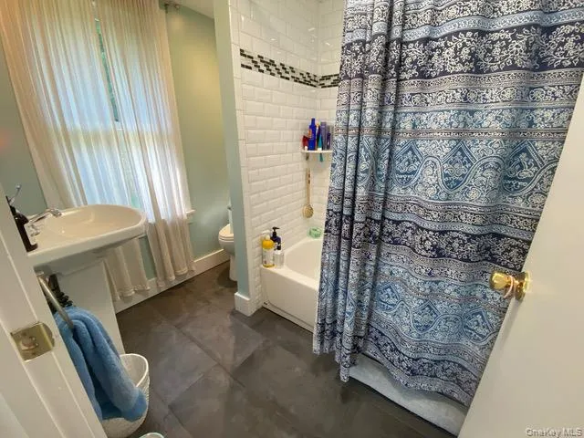 Full bathroom featuring shower / tub combo with curtain and toilet Full bathroom featuring shower / tub combo with curtain and toilet