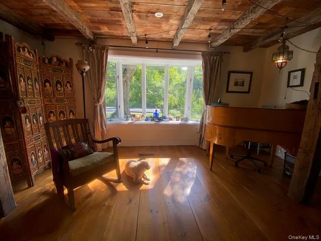 Living area with a wooden ceiling with exposed beams and wood-type flooring Living area with a wooden ceiling with exposed beams and wood-type flooring