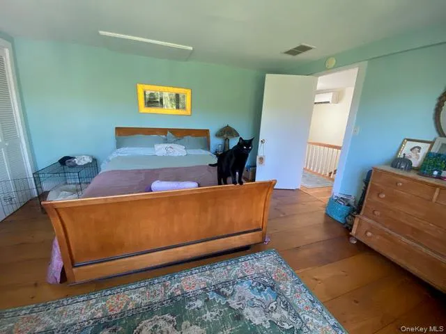 Bedroom featuring hardwood / wood-style floors and a wall mounted air conditioner Bedroom featuring hardwood / wood-style floors and a wall mounted air conditioner