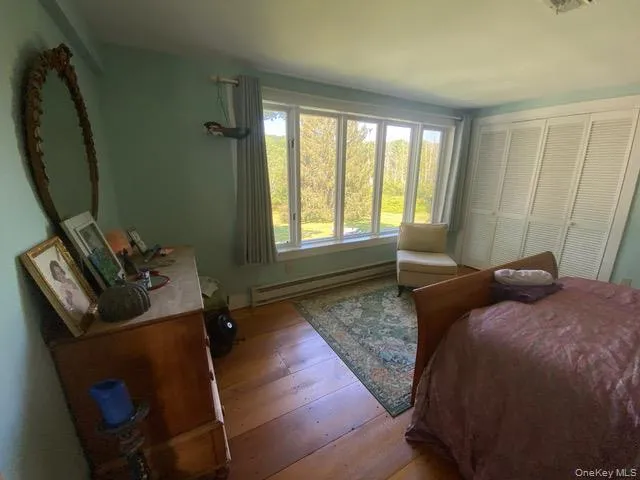 Bedroom featuring a baseboard heating unit and wood-type flooring Bedroom featuring a baseboard heating unit and wood-type flooring