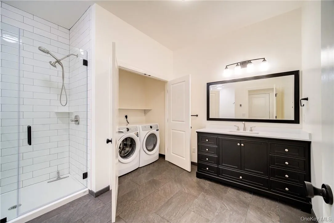 Laundry room featuring dark tile flooring, sink, and washer and clothes dryer Laundry room featuring dark tile flooring, sink, and washer and clothes dryer