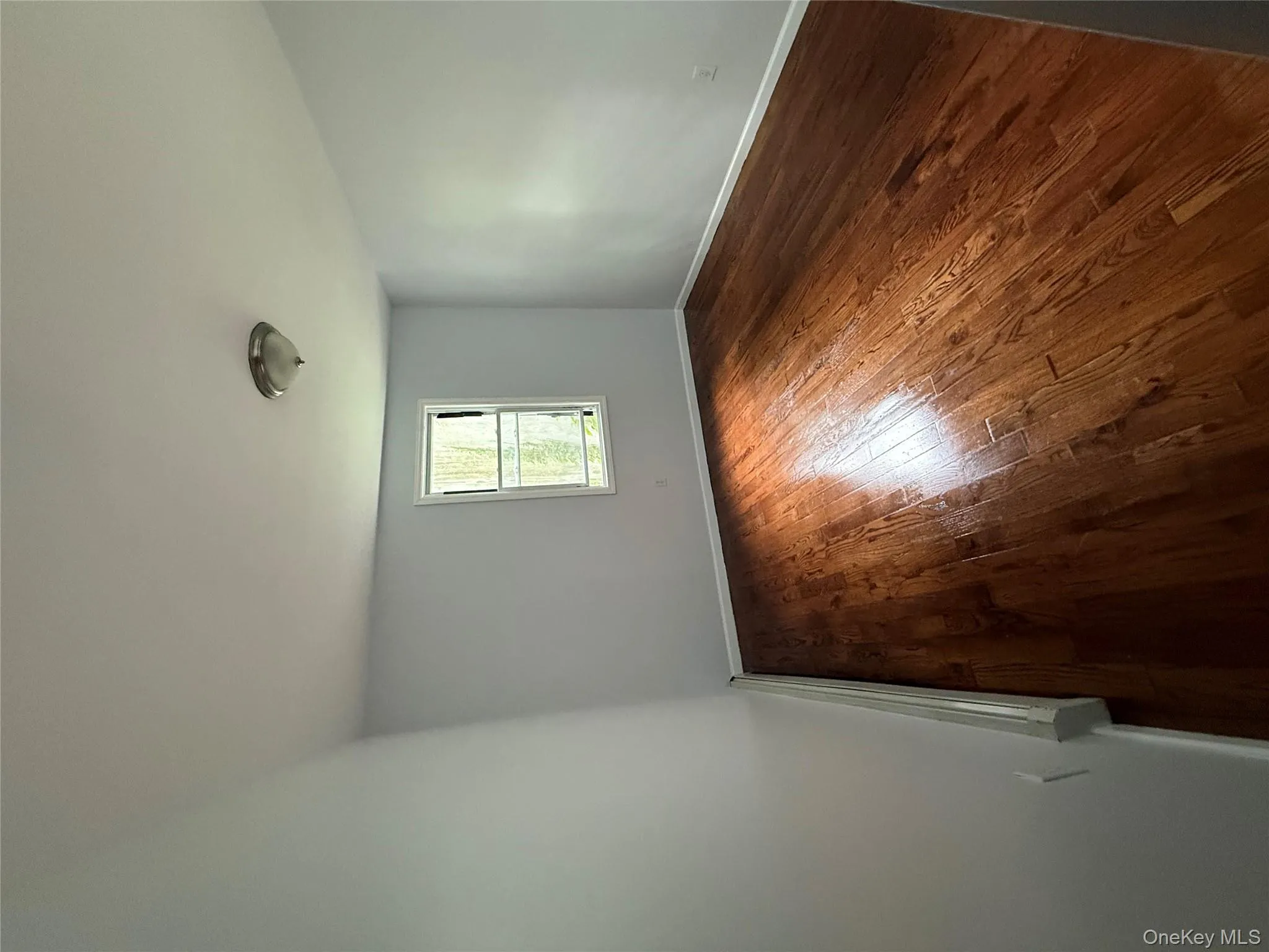 Spare room with dark wood-type flooring and a baseboard heating unit Spare room with dark wood-type flooring and a baseboard heating unit