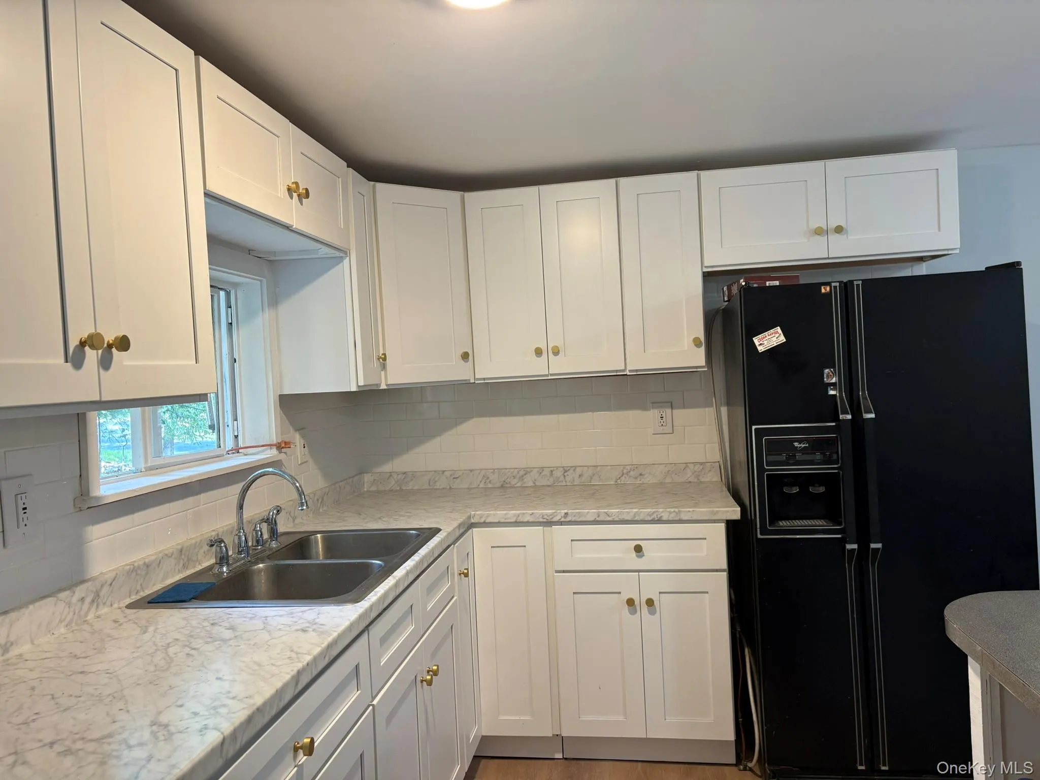Kitchen with black fridge, white cabinets, and backsplash Kitchen with black fridge, white cabinets, and backsplash