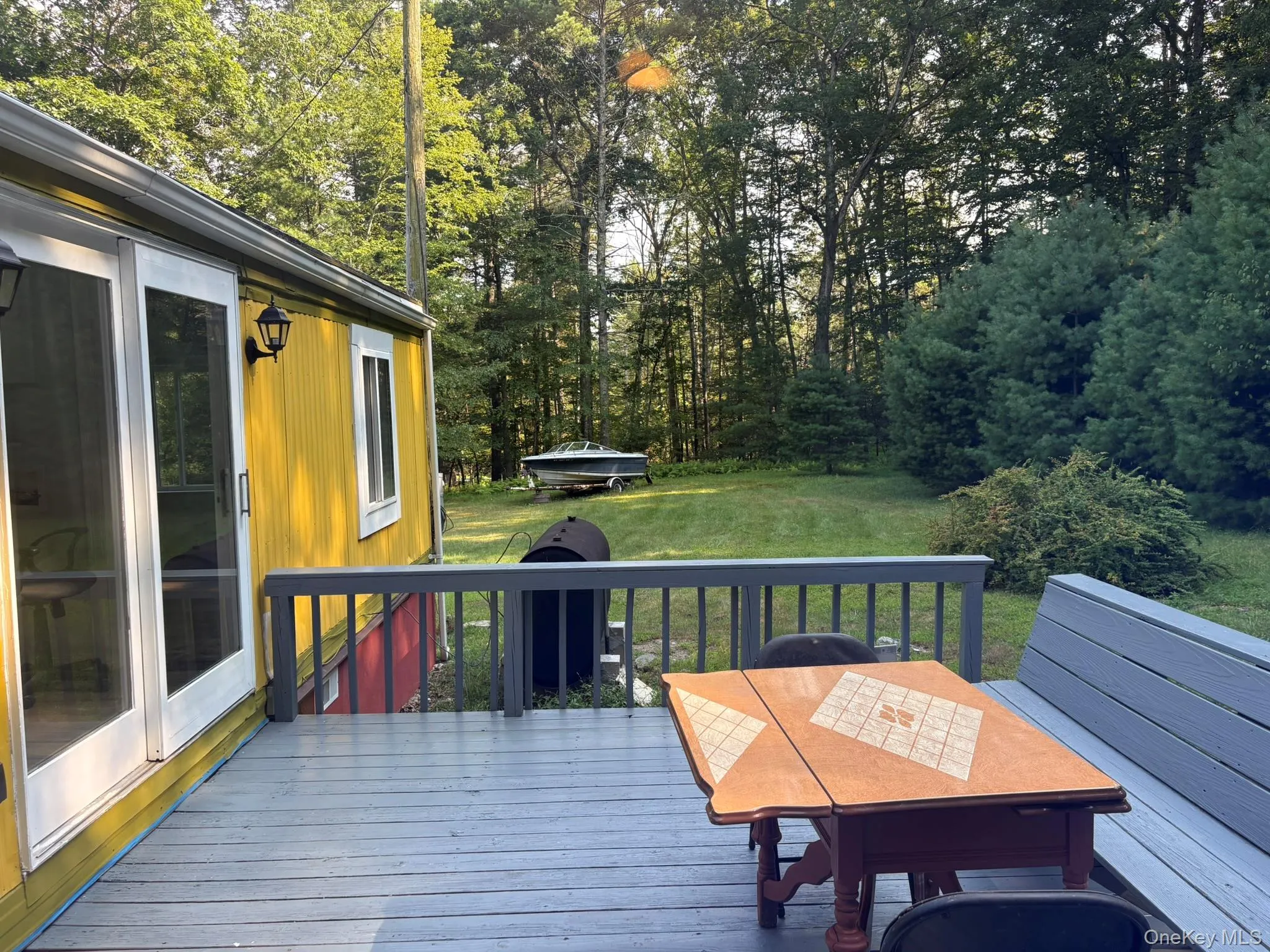 Wooden deck featuring outdoor dining area, a yard, and view of wooded area Wooden deck featuring outdoor dining area, a yard, and view of wooded area