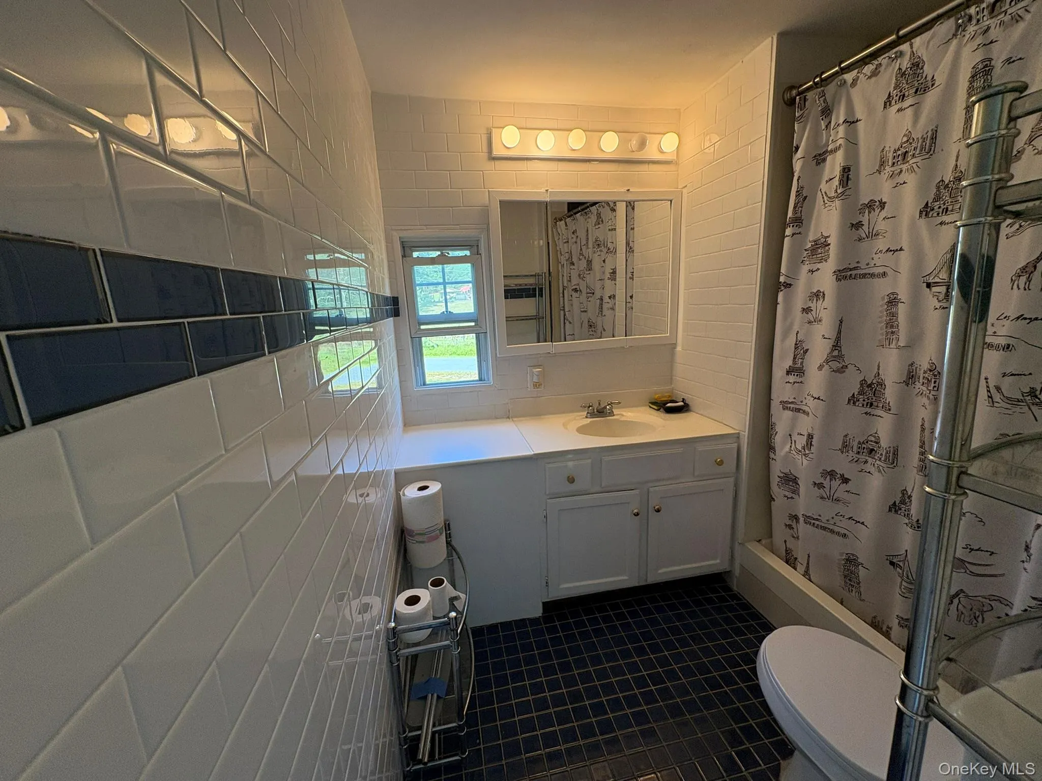 Bathroom featuring tile walls, a shower stall, vanity, and dark tile patterned flooring Bathroom featuring tile walls, a shower stall, vanity, and dark tile patterned flooring