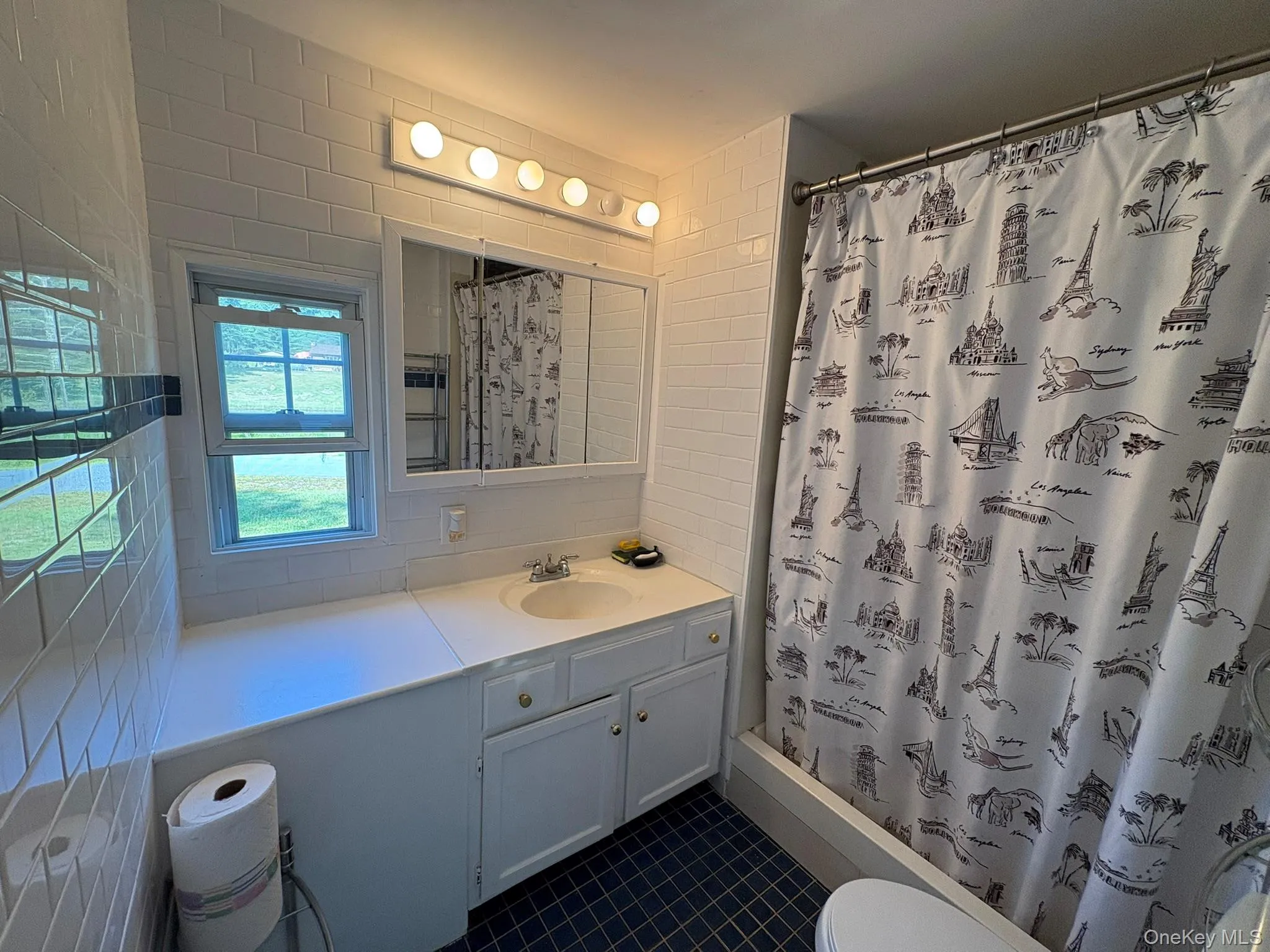 Bathroom with vanity, tile walls, dark tile patterned floors, and a stall shower Bathroom with vanity, tile walls, dark tile patterned floors, and a stall shower