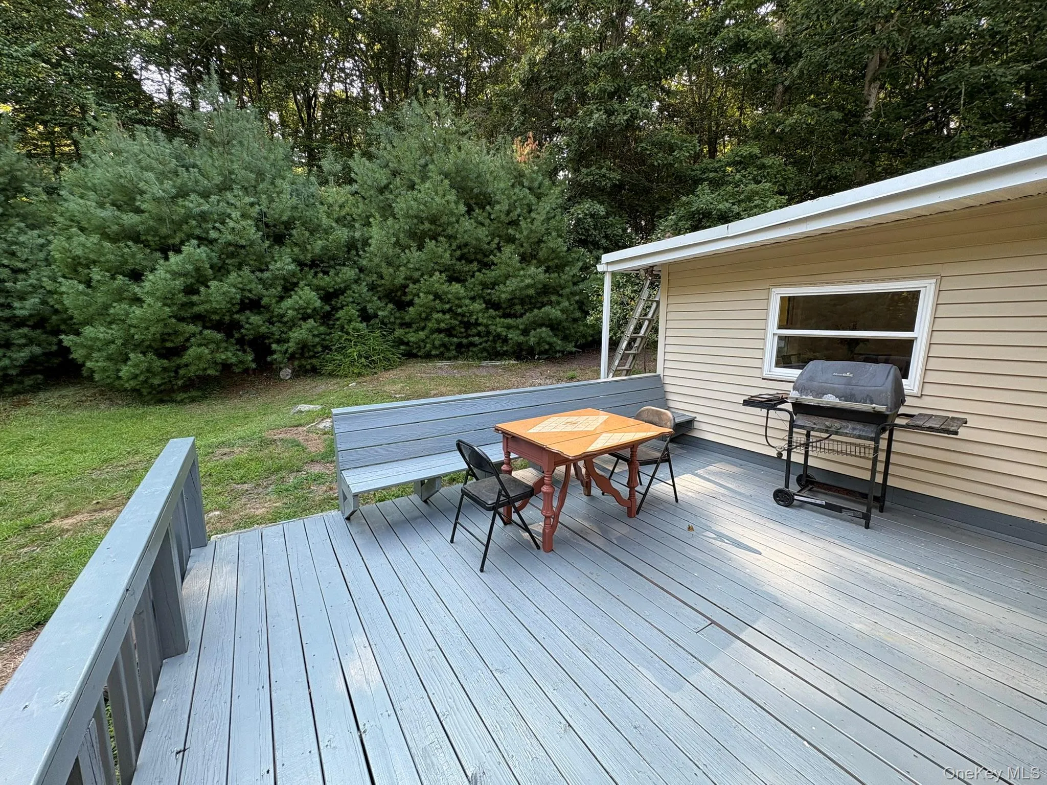 Wooden terrace with grilling area, outdoor dining area, and a lawn Wooden terrace with grilling area, outdoor dining area, and a lawn
