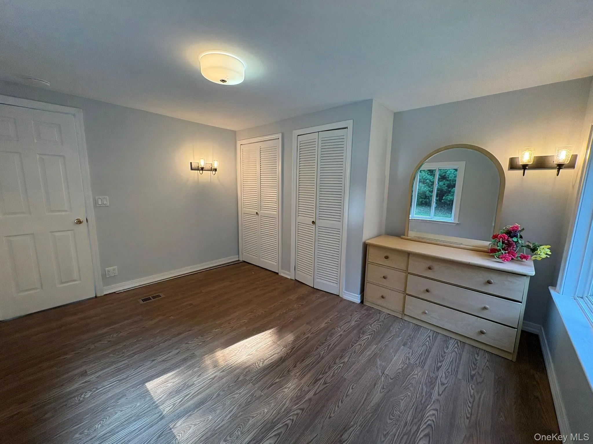 Unfurnished bedroom featuring two closets and dark wood-style flooring Unfurnished bedroom featuring two closets and dark wood-style flooring