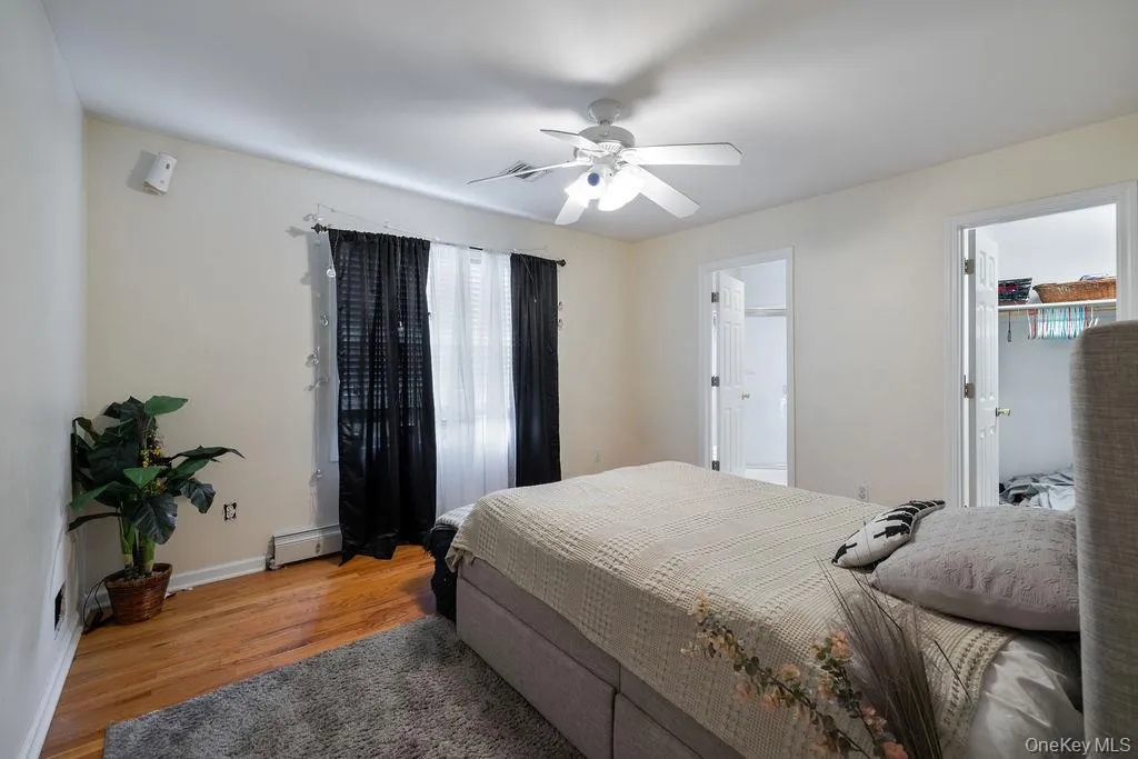 Bedroom with light wood-type flooring, baseboard heating, and ceiling fan Bedroom with light wood-type flooring, baseboard heating, and ceiling fan