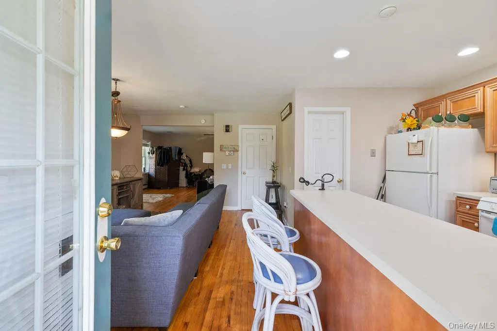 Kitchen with light countertops, white appliances, light wood-type flooring, brown cabinets, and recessed lighting Kitchen with light countertops, white appliances, light wood-type flooring, brown cabinets, and recessed lighting