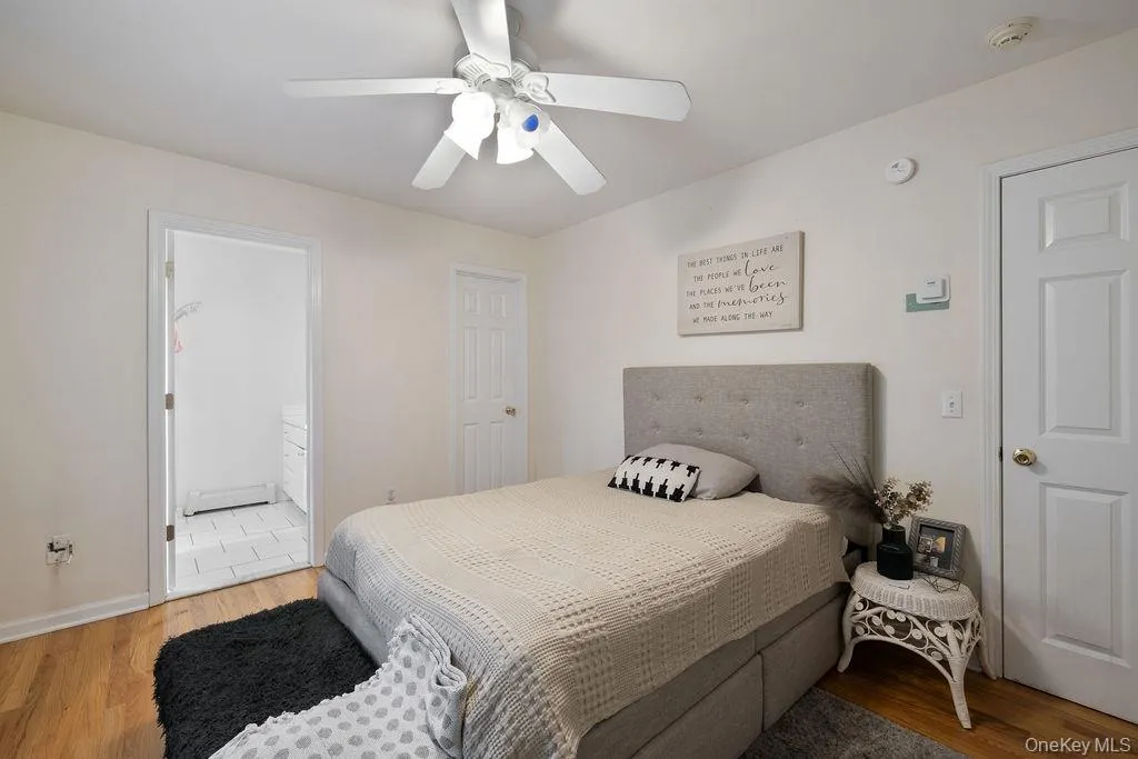 Bedroom with wood finished floors, baseboard heating, a ceiling fan, and ensuite bath Bedroom with wood finished floors, baseboard heating, a ceiling fan, and ensuite bath
