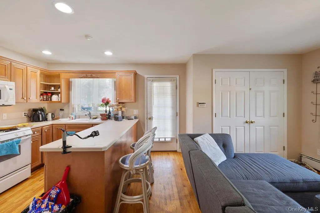Kitchen featuring light countertops, light wood finished floors, white appliances, open shelves, and recessed lighting Kitchen featuring light countertops, light wood finished floors, white appliances, open shelves, and recessed lighting
