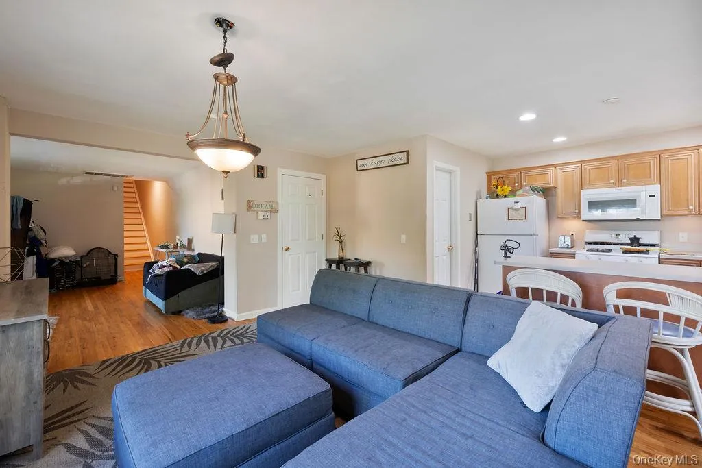 Living room featuring light wood-type flooring, stairway, and recessed lighting Living room featuring light wood-type flooring, stairway, and recessed lighting