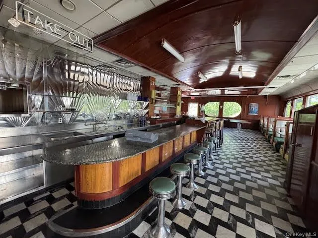 Bar area with healthy amount of natural light, vaulted ceiling, dark floors, and dark countertops Bar area with healthy amount of natural light, vaulted ceiling, dark floors, and dark countertops