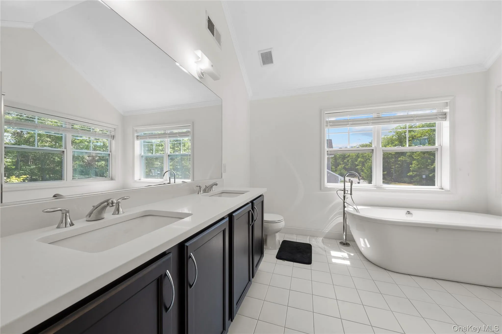 Full bathroom featuring a freestanding bath, crown molding, light tile patterned flooring, and vaulted ceiling Full bathroom featuring a freestanding bath, crown molding, light tile patterned flooring, and vaulted ceiling