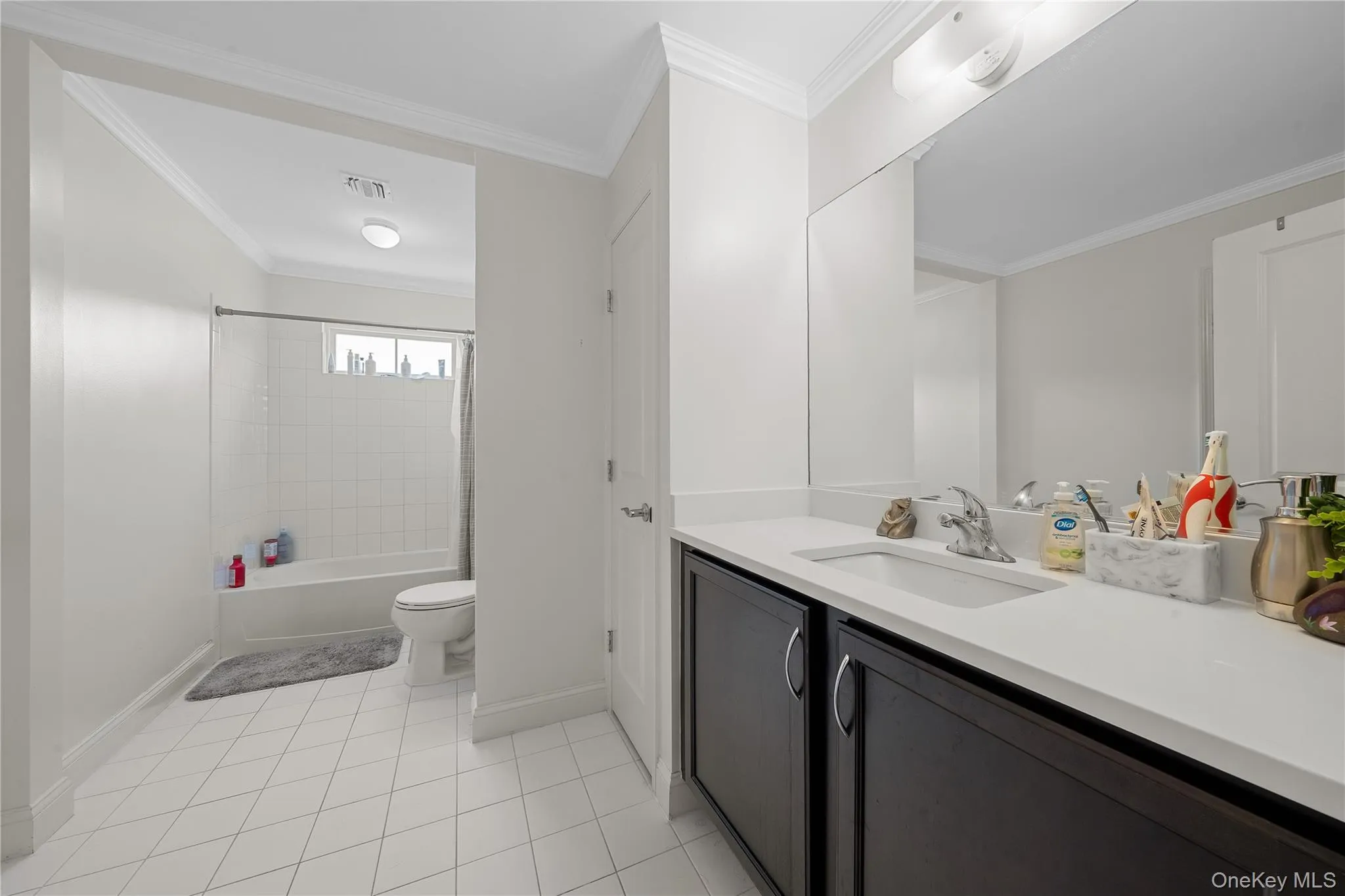 Bathroom with crown molding, shower / tub combo, vanity, and light tile patterned flooring Bathroom with crown molding, shower / tub combo, vanity, and light tile patterned flooring