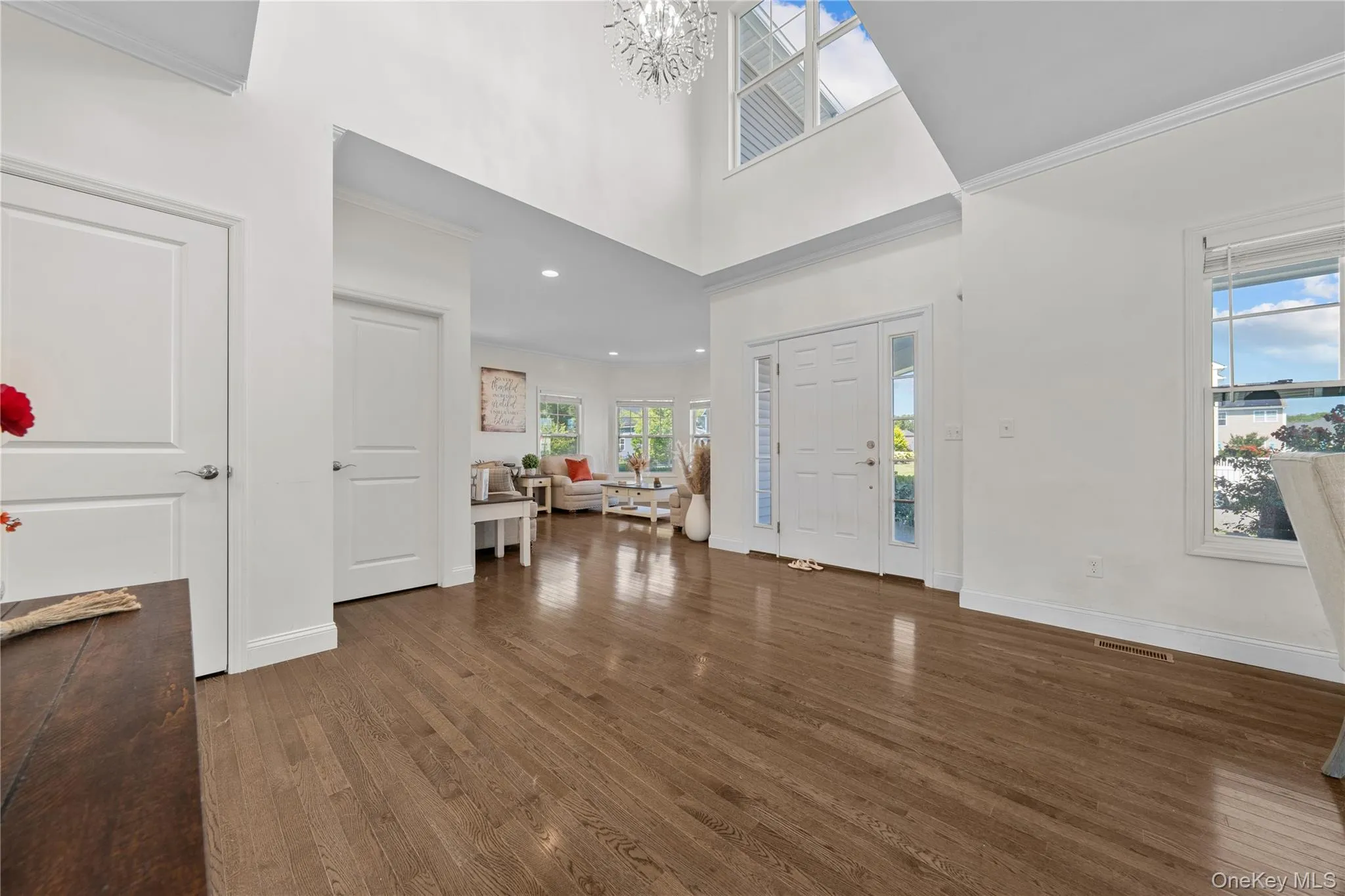 Entrance foyer with ornamental molding, a towering ceiling, healthy amount of natural light, dark wood finished floors, and a chandelier Entrance foyer with ornamental molding, a towering ceiling, healthy amount of natural light, dark wood finished floors, and a chandelier